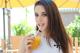 A woman holding a glass of orange juice with a straw.