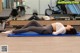 A woman laying on a blue mat in a gym.