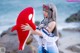 A woman holding a red and white stuffed animal on a beach.