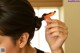 A woman is combing her hair with an orange comb.