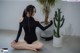 A woman sitting on the floor next to a potted cactus.