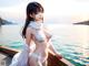 A woman in a white bikini standing on a dock by the water.