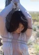 A woman tied up to a palm tree in the desert.